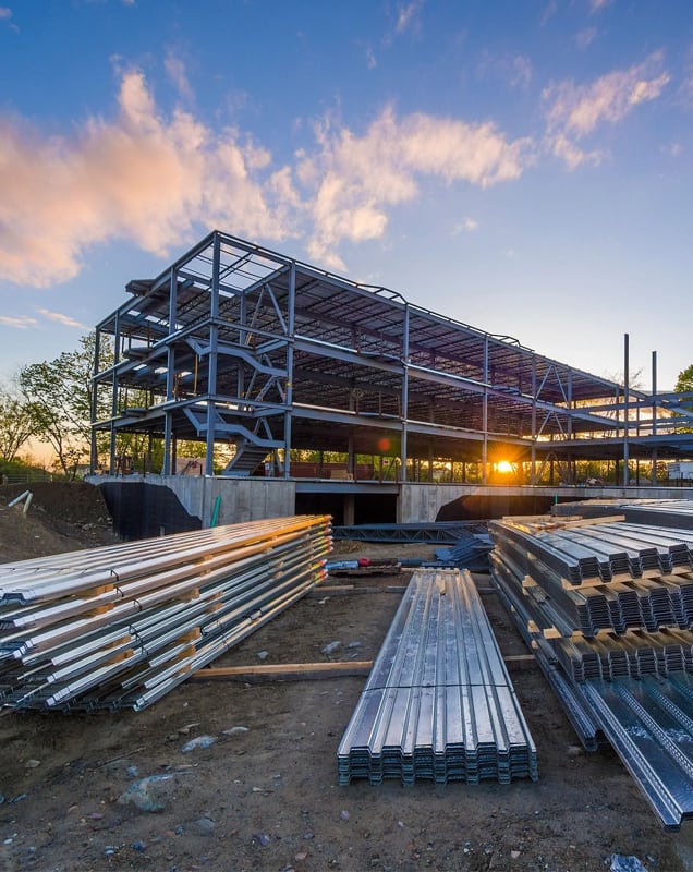 Multi-story steel frame construction site at sunset